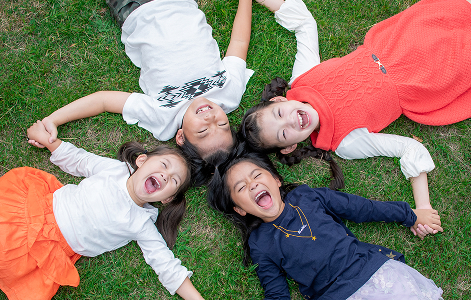 芝生の上で手をつないで輪になる仲良し４人組